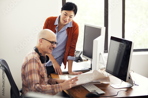 Woman and man smiling and looking at blueprint photo