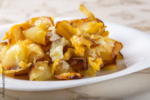 Fries with smashed eggs on white plate