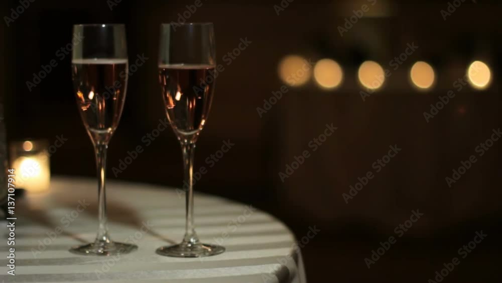 Light shining across two champagne glasses on a table. Light shining across two champagne glasses on a table.