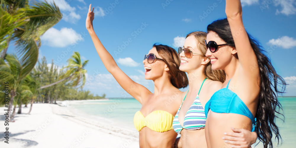 happy young women in bikinis on summer beach