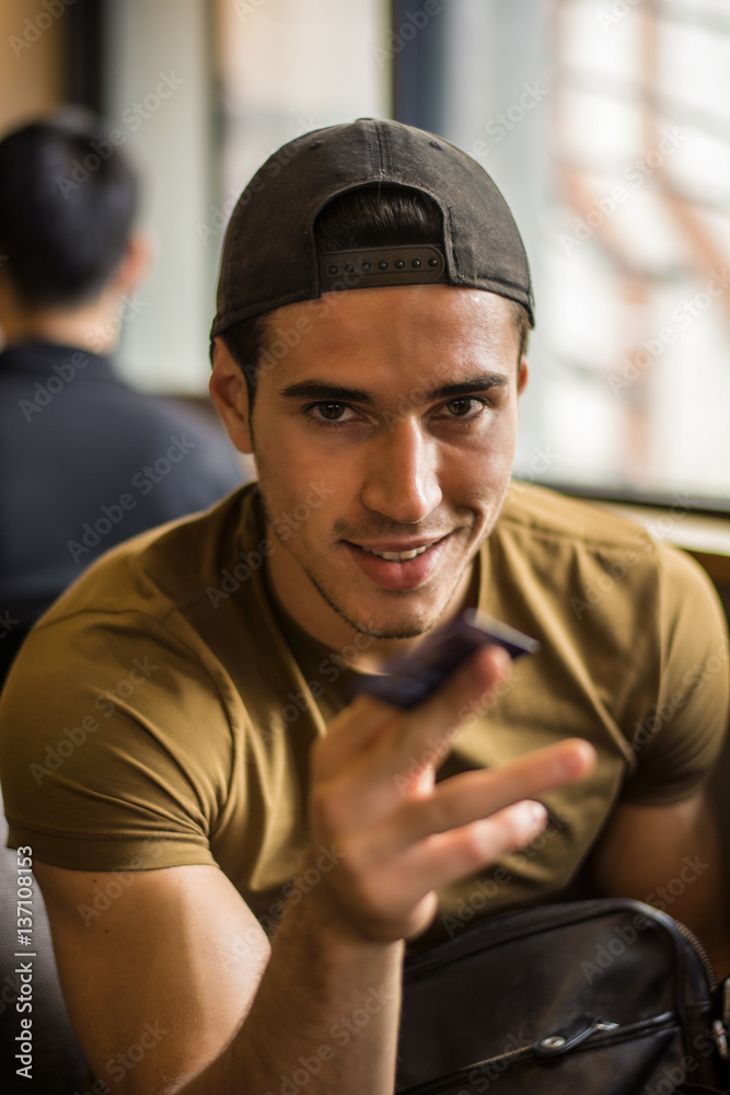 Vertical indoors shot of young smiling man giving a credit card and looking at camera. Vertical indoors shot of young smiling man giving a credit card and looking at camera.