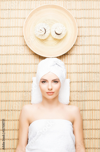 Beautiful, young and healthy woman in spa salon on bamboo mat. Spa, health and healing concept.