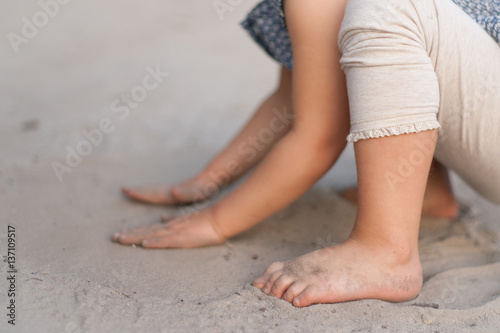 Baby girl sitting on a beach playing with sand with dirty hands and legs