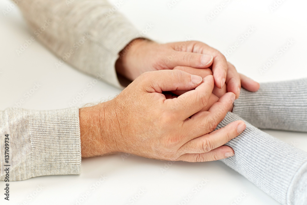 close up of old man and young woman holding hands