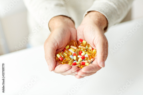 close up of senior man hands holding pills