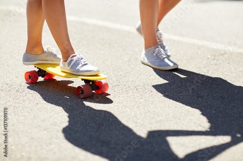 feet of teenage couple riding skateboard on road