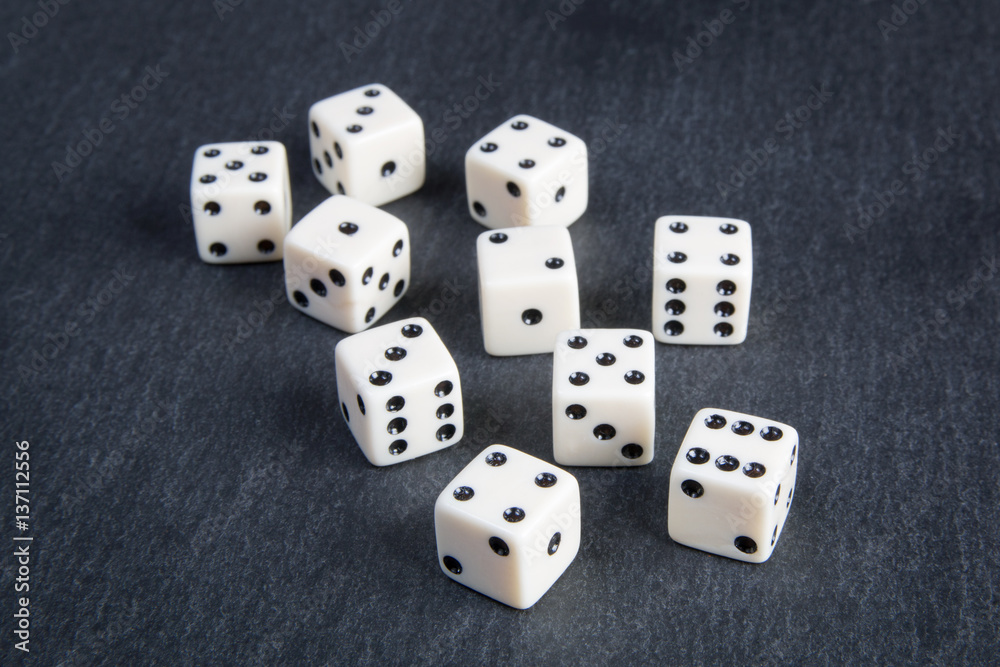 small dice on dark stone background small dice on dark stone background