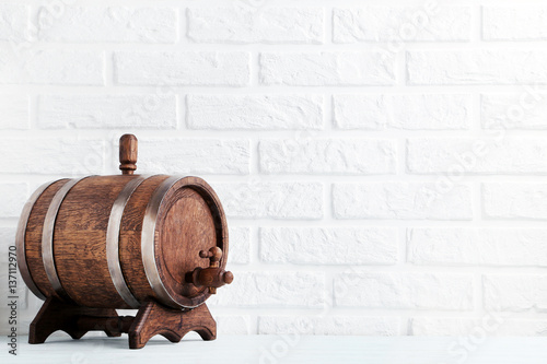 Wooden barrel with iron rings on brick wall background