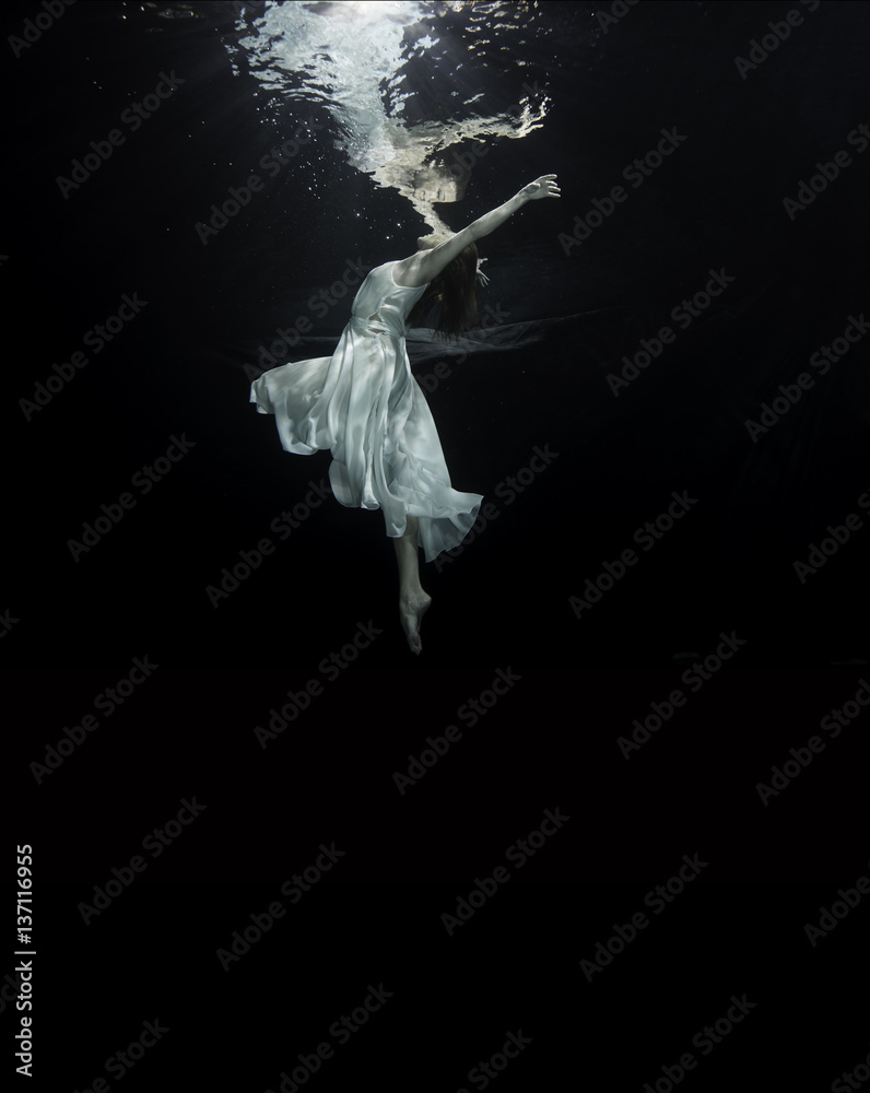 Fototapeta premium Young female ballet dancer dancing underwater