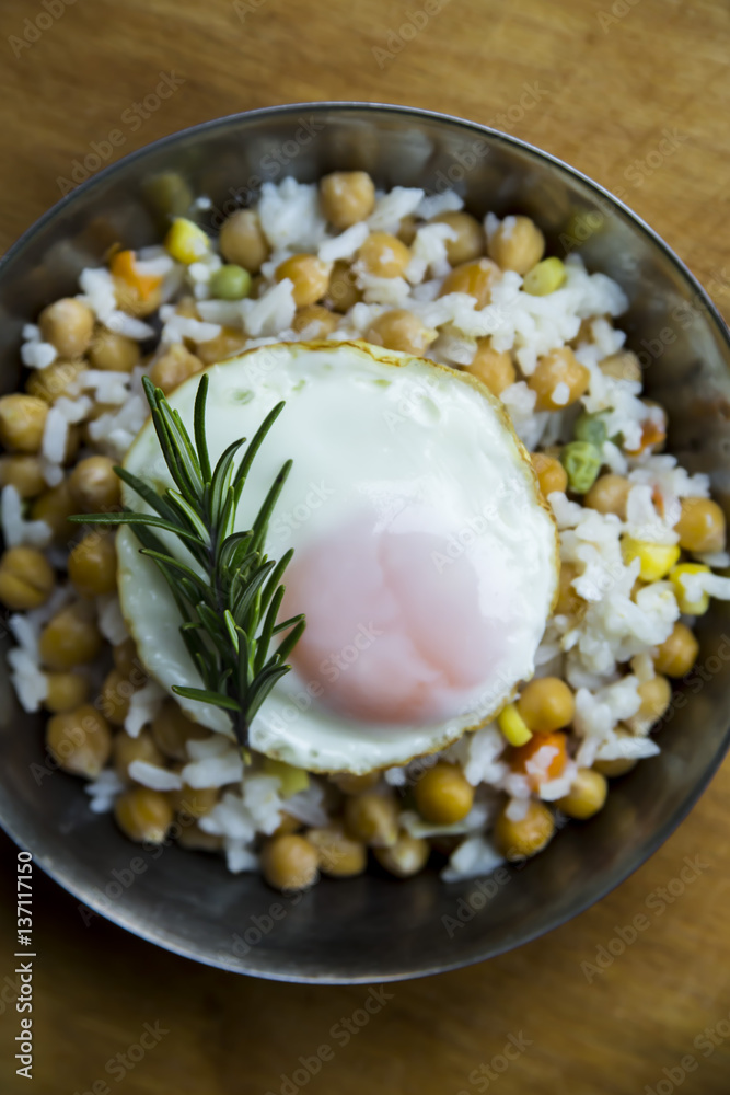 Fried egg on a frying pan with a little chickpea, rice and rosemary Fried egg on a frying pan with a little chickpea, rice and rosemary