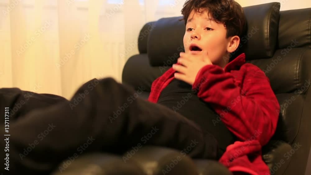 Excited young boy child lying on a sofa and watching horror movie at home Excited young boy child lying on a sofa and watching horror movie at home