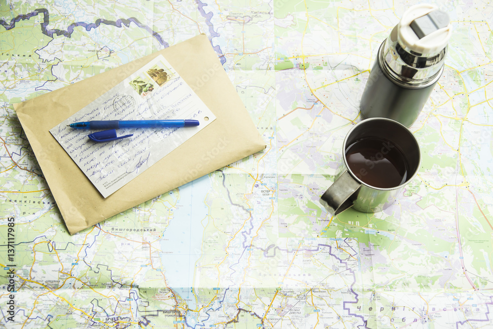 Map & Travel. thermos mug camp, an envelope and a postcard from your trip. on the map background