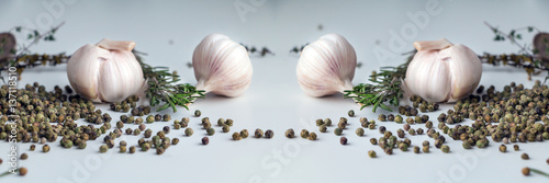 Green peppercorns - pepe verde - famous spice of italian cuisine on white table with garlic bulbs, thyme twig and spoon. Selective focus. Wide panoramic image.