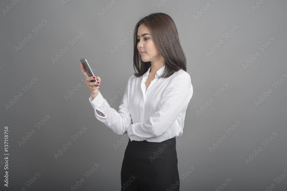 Beautiful business Woman using smartphone on grey background Beautiful business Woman using smartphone on grey background