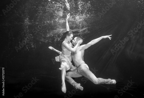 Yong couple of ballet dancers dacing underwater