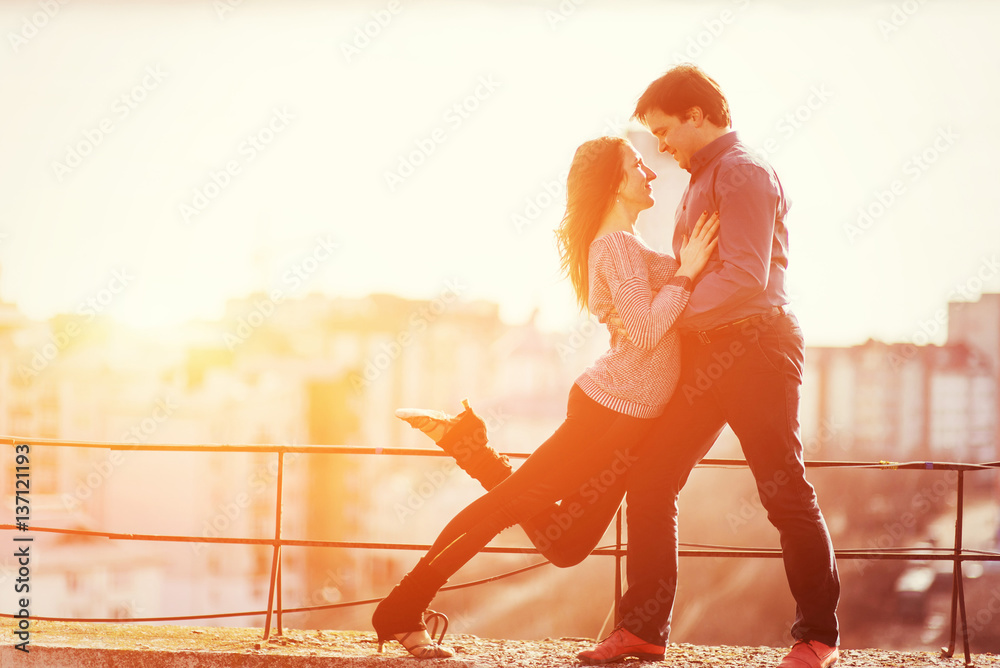 young couple dancing on the roof of a tall building