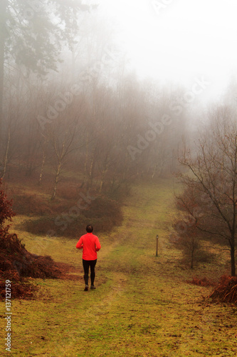 Man jogging in woodland on a foggy misty morning