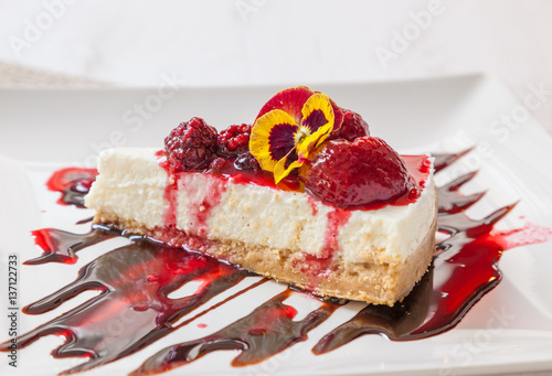 A slice of cheesecake with strawberry and raspberry sauce.
