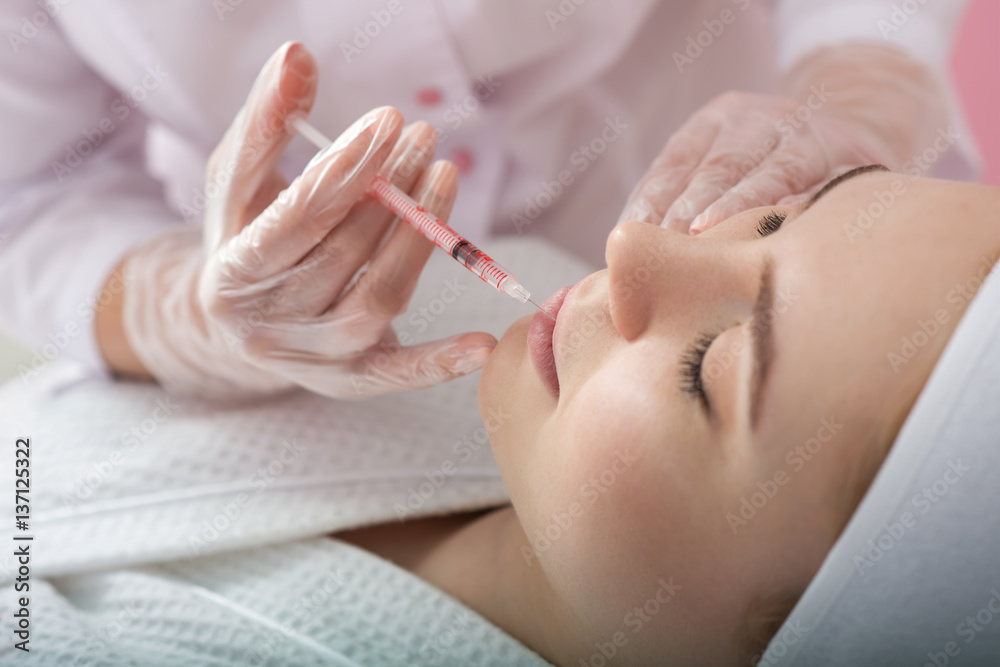 Young woman gets beauty facial injections in salon.