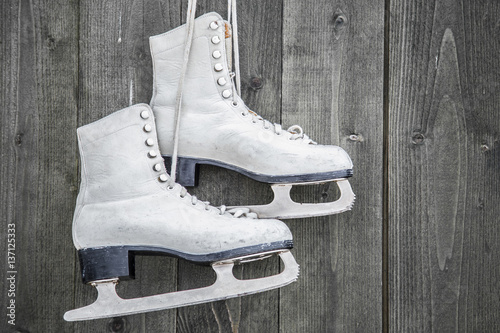 Old white skates on the wooden wall. Weekends activities outdoor in cold weather.