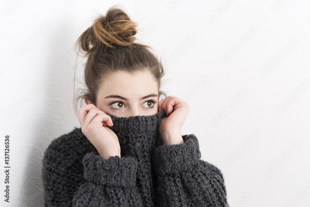Young woman covering her mouth with a sweater on a white background. Young woman covering her mouth with a sweater on a white background.