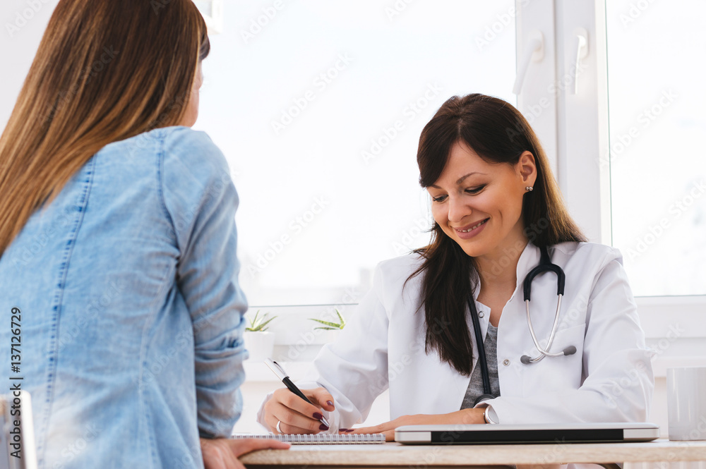 Female doctor writing prescription to patient Female doctor writing prescription to patient