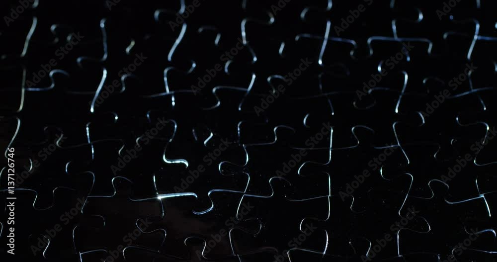 A creative completes the black or white light puzzle putting the last missing piece. Concept: cooperation, teamwork, creativity, and access solution.