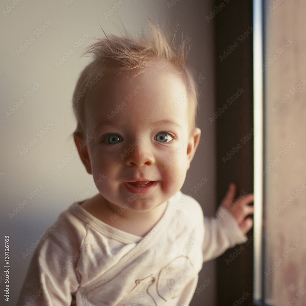Portrait of a little boy who is sitting in the window and smiling. emotions concept.