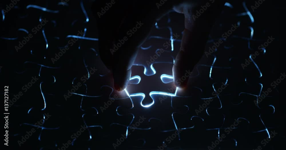 A creative completes the black or white light puzzle putting the last missing piece. Concept: cooperation, teamwork, creativity, and access solution.