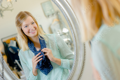 Canvas Print Lady trying on scarf, looking at reflection in mirror