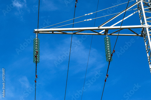 Supports high-voltage power lines against the blue sky with clouds. Electrical industry
