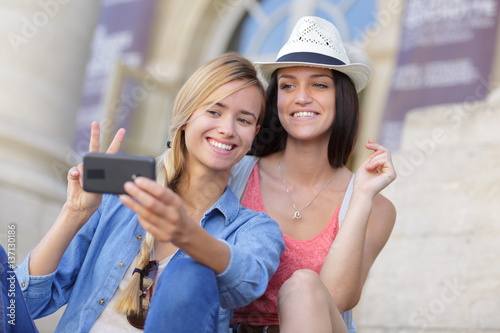 cheerful tourist female friends taking photos of themselves © auremar