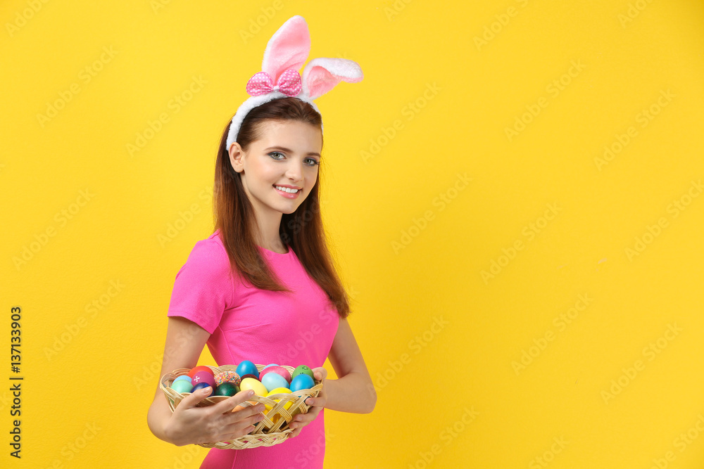 Beautiful girl with bunny ears and Easter eggs on color background Beautiful girl with bunny ears and Easter eggs on color background
