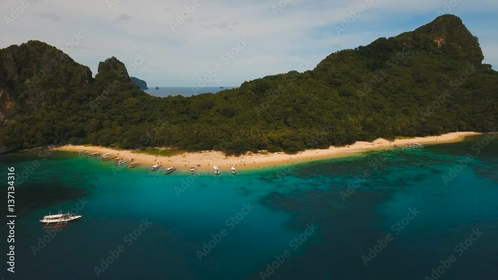 Beautiful beach with boats and tourists. Tropical bay in El Nido. Aerial view: bay and the tropical island. Aerial video. Tropical lagoon with turquoise water and white sand. Seascape: mountains Beautiful beach with boats and tourists. Tropical bay in El Nido. Aerial view: bay and the tropical island. Aerial video. Tropical lagoon with turquoise water and white sand. Seascape: mountains