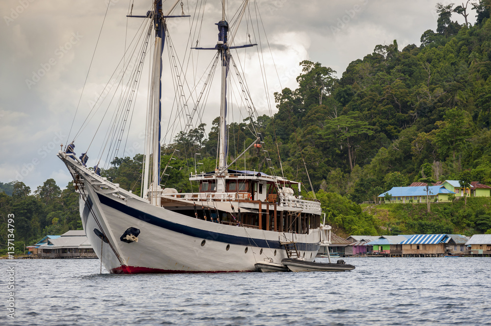 Indonesian Schooner anchored in Raja Ampat, Misool Island, West Papua. A traditional phinisi schooner is anchored off Aduwey Village in the Raja Ampat area of Indonesia. Indonesian Schooner anchored in Raja Ampat, Misool Island, West Papua. A traditional phinisi schooner is anchored off Aduwey Village in the Raja Ampat area of Indonesia.