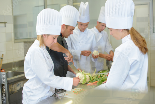 Team of trainee chefs preparing vegetables