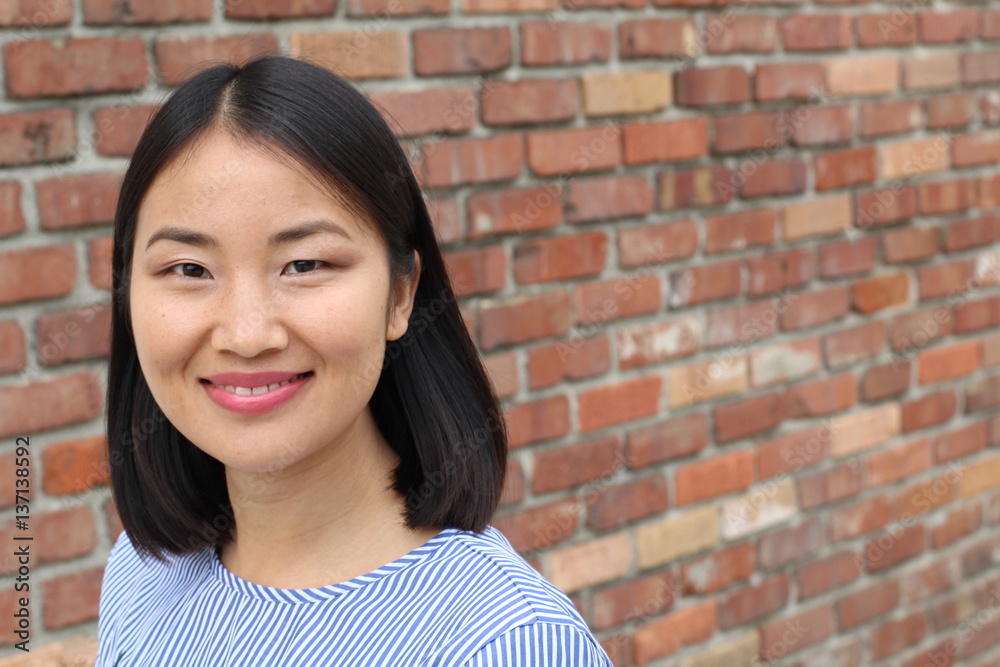Asian woman smiling isolated on brick wall with space for copy Asian woman smiling isolated on brick wall with space for copy