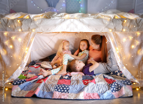 Foto Young woman and cute children playing in hovel at home