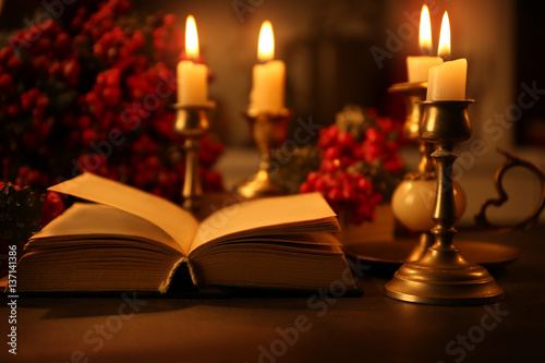 Open Bible and burning candles on table