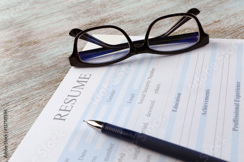 Blank resume form and eyeglasses on wooden table  closeup