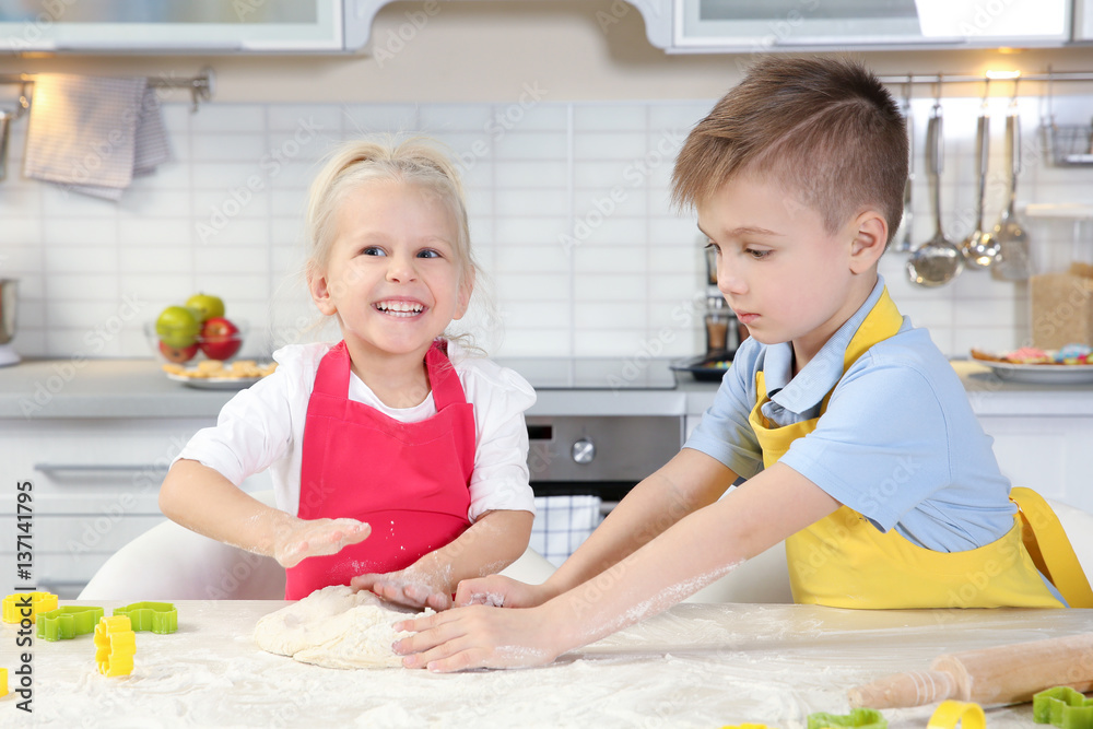 Cute little children making Easter cookies at kitchen