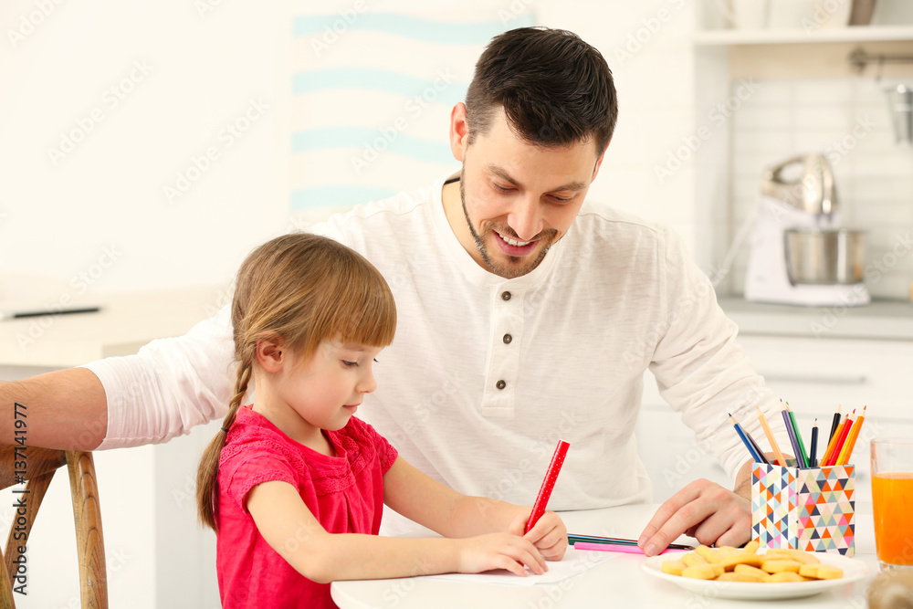 Fototapeta premium Young man and little girl drawing at kitchen table