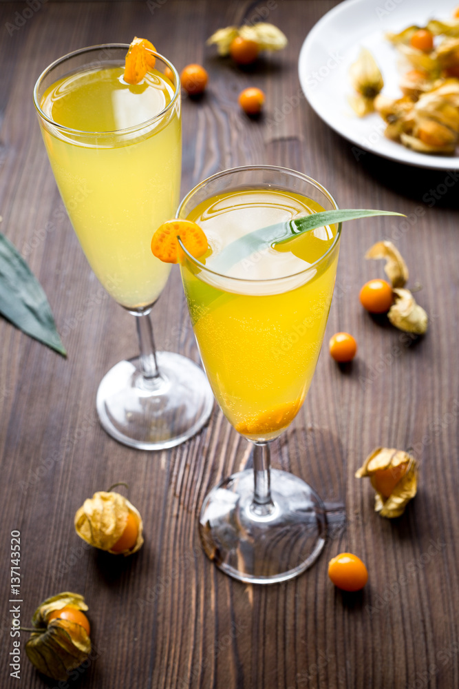 cocktail with physalis in glass on wooden background cocktail with physalis in glass on wooden background