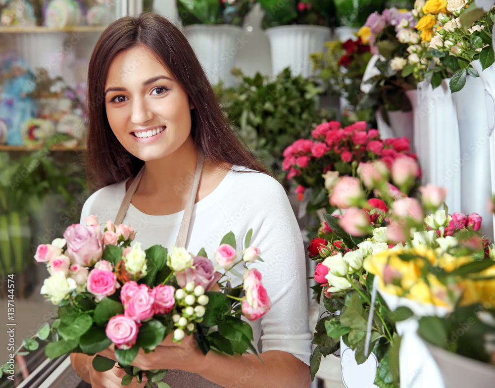 Pretty young florist with bouquet in flower shop