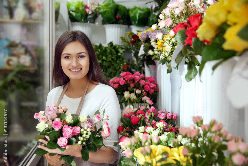 Pretty young florist with bouquet in flower shop