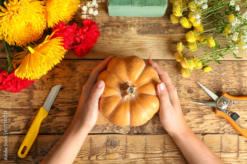 Florist at work. Pumpkin, flowers and tools on wooden background, top view