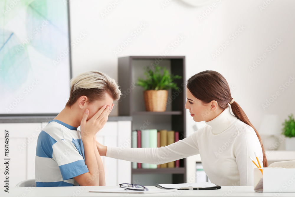 Fototapeta premium Young female psychologist working with teenager boy in office