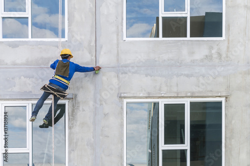 The worker man abseiling with rope on construction site