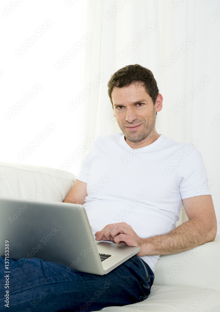 handsome attractive man at home lying on couch working as freelancer with computer laptop handsome attractive man at home lying on couch working as freelancer with computer laptop
