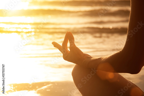 Harmony and peaceful. Young woman make meditation at sunset sea beach. Mudra gesture